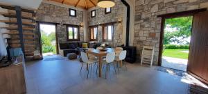- un salon avec une table, des chaises et un mur en pierre dans l'établissement Kastania Villas- Villa K3, à Pouríon