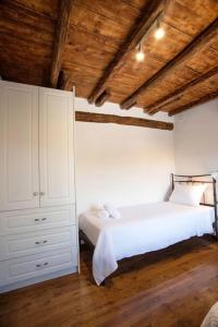 ein Schlafzimmer mit einem weißen Bett und einer Holzdecke in der Unterkunft Αναμνήσεις - παραδοσιακό εξοχικό σπίτι με μεγάλο κήπο in Galaxidi