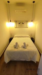 1 dormitorio con 1 cama blanca y 2 toallas en WISH SUITE MARIA AUXILIADORA DE SEVILLA, en Sevilla