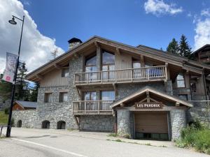 a us resort building with a balcony on top of it at Chalets Les Perdrix - Mountain Collection in La Rosière