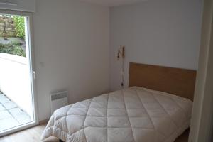 uma cama branca num quarto com uma janela em pleneuf val andre appart vue mer 2 à 4 personnes em Pléneuf-Val-André