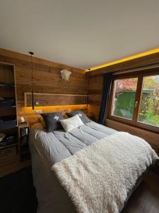 1 dormitorio con 1 cama grande y pared de madera en CHALET MONT BLANC, en Combloux