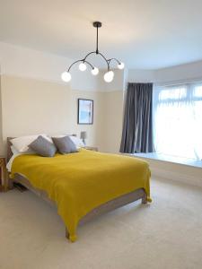 a bedroom with a large bed with a yellow blanket at 1 Ashford Road Guesthouse in Redhill