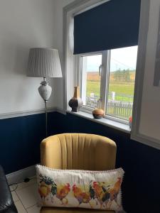una silla amarilla sentada en una habitación con ventana en Windmill cottage, en Donegal