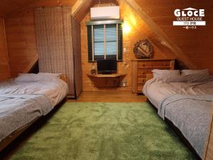 a bedroom with two beds and a television in a cabin at GLOCE伊東一碧house 自然が溢れ閑静なエリアにあるログハウスを貸切り in Ito