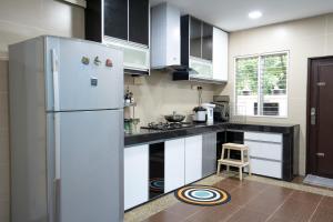 a kitchen with a refrigerator and a stool in it at Spacious 5 Bedroom Holiday Home Perfect for Gatherings BBQs Rumah Holiday Big 5BR House for 20 Guests - Ideal for Family Celebrations 宽敞整栋别墅 5 间大房间 20人 家庭聚会 生日派对 烧烤聚会 in Kuala Lumpur