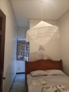 a bedroom with a bed with a chandelier above it at Pearl Motel Buloba in Buloba