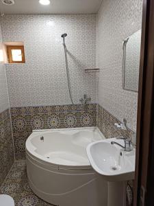 ein Badezimmer mit einer Badewanne und einem Waschbecken in der Unterkunft Khiva Ibrohim Guest House in Xiva