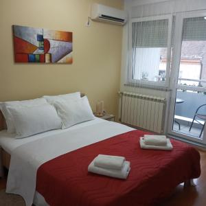 a bedroom with a large bed with two towels on it at Angellina Apartmani in Sremska Mitrovica
