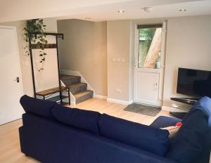a living room with a blue couch and a tv at Owl Tree Cottage with access to Alice Holt in Farnham