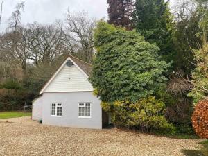 uma pequena garagem branca ao lado de um grande arbusto em Owl Tree Cottage with access to Alice Holt em Farnham