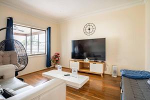 Wollongong station holiday house with Wi-Fi,75 Inch TV, Netflix,Parking,Beach في ولونغونغ: غرفة معيشة مع أريكة وتلفزيون