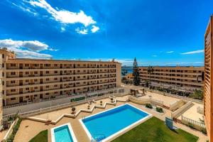 アロナにあるTenerifeopenhome bright penthouse on the beach Los Cristianosの大きな建物で、目の前にスイミングプールがあります。