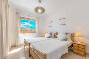 a white bedroom with two beds and a window at Tenerifeopenhome bright penthouse on the beach Los Cristianos in Arona