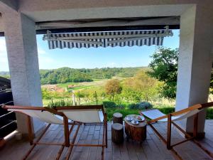 a porch with two chairs and a table and a view at GREENHILLS Relax & Holiday House in Kebel