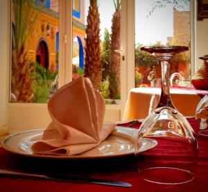 einen Teller mit einer Serviette und einem Weinglas auf dem Tisch in der Unterkunft Riad Jasmine Sud in Zagora