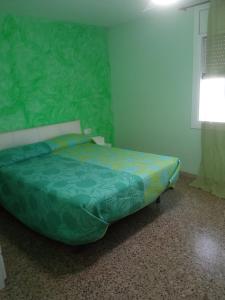 uma cama num quarto com uma parede verde em Cal Turuta em Vilanova i la Geltrú