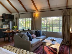 a living room with a couch and a table at Yellowwoods Farm - POOL COTTAGE (self-catering) in Curryʼs Post