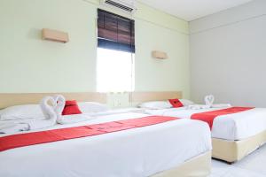 two beds in a room with white walls and a window at RedDoorz Plus at Sunrise Hotel Sanur in Sanur
