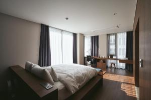 um quarto com uma cama, uma secretária e janelas em Good Ol' Days Hotel em Busan