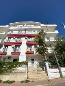 een hoog wit gebouw met rode ramen en trappen bij Nurer Apart Otel in Antalya