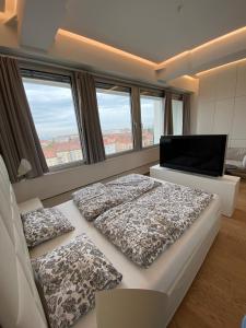 sypialnia z 2 łóżkami, telewizorem i oknami w obiekcie Key Residences Vienna w Wiedniu