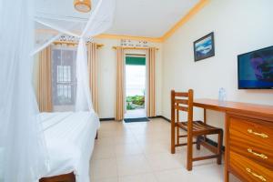 a bedroom with a bed and a desk and a window at Mirembe Resort Beach Hotel Ssese in Kalangala