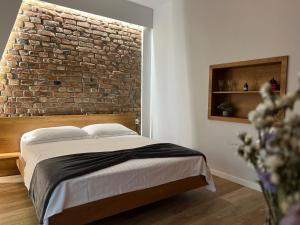 Cama en habitación con pared de ladrillo en KONI's Studio Apartments, en Tirana
