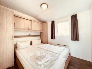 a small bedroom with a bed with white sheets at Regenbogen Suhrendorf in Ummanz