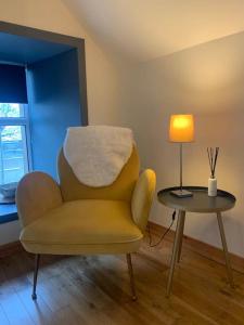 a yellow chair sitting next to a table with a lamp at Orkney Staycations - Orcadale in Orkney