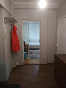 um corredor com uma porta que leva a uma sala com um quarto em 1-к. Карасай батыра 110 em Almaty