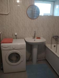 uma casa de banho com uma máquina de lavar roupa e um lavatório em 1-к. Карасай батыра 110 em Almaty