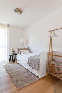 a white bedroom with a large white bed and a desk at Ferienwohnung Rosenstrasse in Dornbirn