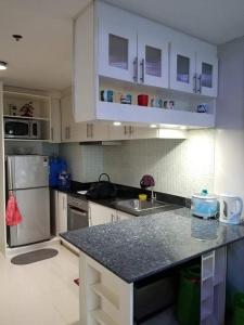 cocina con armarios blancos y encimera negra en Sea Residences Homey Condo by DNJ, en Manila