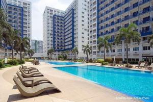 a large swimming pool in a city with tall buildings at Sea Residences Homey Condo by DNJ in Manila
