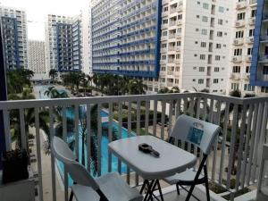 einen Tisch und Stühle auf einem Balkon mit Poolblick in der Unterkunft Sea Residences Homey Condo by DNJ in Manila