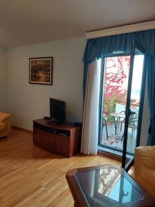 a living room with a television and a glass table at Plava Vila Beach Apartments Sveti Stefan in Sveti Stefan
