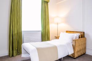 a bedroom with a white bed and a green curtain at Astor Court Hotel in London