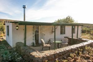 ein kleines Haus mit einer Steinmauer in der Unterkunft Sunbird Cottage in Graaff-Reinet