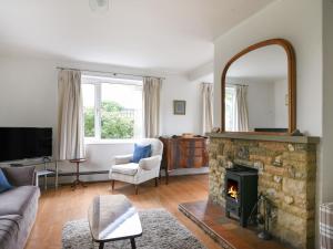 a living room with a fireplace and a mirror at Hollycombe Cottage in Wootton Fitzpaine