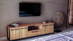 um centro de entretenimento de madeira com uma televisão na parede em Bula Villa em Umeanyar