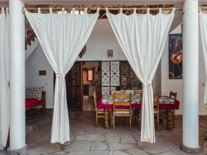 a dining room with a table and white curtains at Villa Samawati - Rafiki Village in Watamu