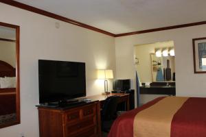 a hotel room with a bed and a flat screen tv at Sanger Inn in Sanger