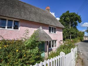 a pink house with a thatched roof at Old Cross Cottage in Whitchurch Canonicorum