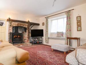 sala de estar con chimenea y TV en Old Cross Cottage, en Whitchurch Canonicorum