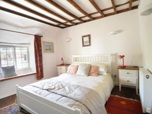 1 dormitorio con cama blanca y ventana en Old Cross Cottage, en Whitchurch Canonicorum