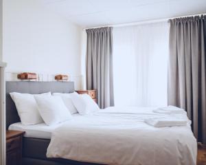 a bedroom with two beds with white sheets and a window at Lofsdalens Fjällhotell & Hotellbyns lägenheter in Lofsdalen