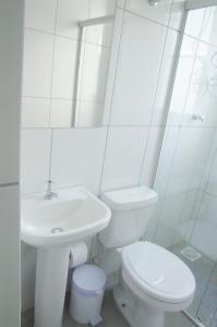 a white bathroom with a toilet and a sink at Studio 900m do centro, prédio com piscina, sauna, academia e lavanderia in São João del Rei