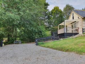 a house with a deck and a bench in front of it at River Cottage in Drumnadrochit