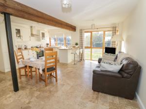 a living room with a couch and a table and a kitchen at Granary Cottage in Southam